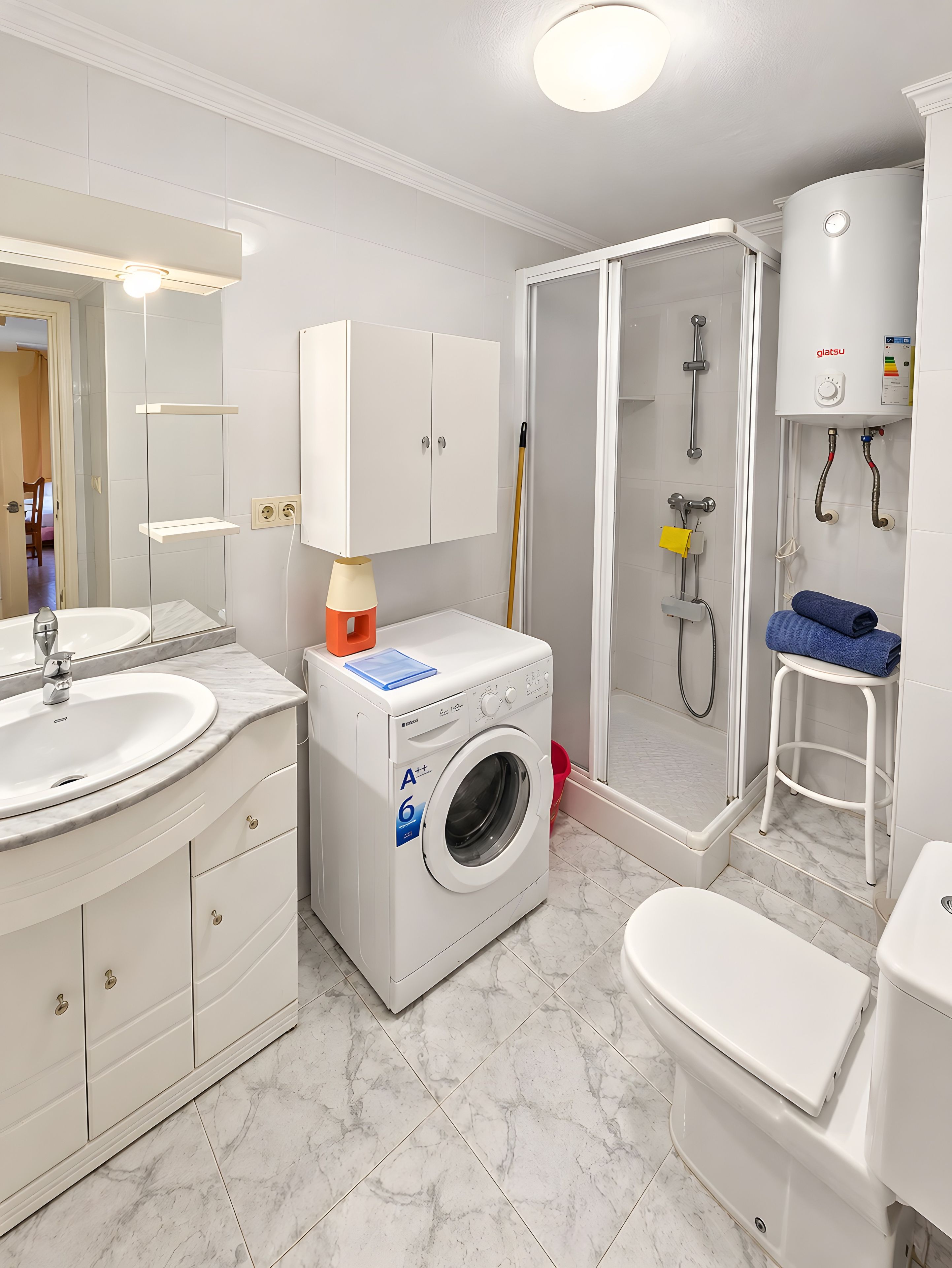 Een moderne badkamer met een ingebouwde wasmachine, een douchecabine en een toilet.
