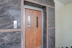 Una puerta de madera con un espejo rectangular y un panel de control con un logotipo.