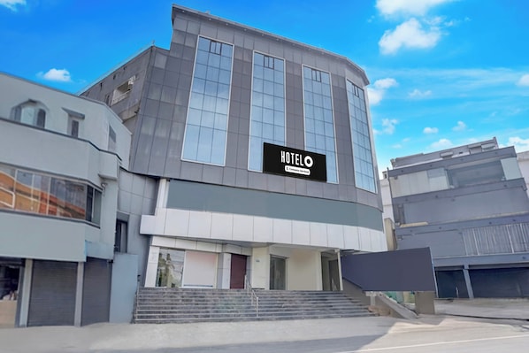A modern hotel building with a prominent sign, a staircase leading to the entrance, and a clear sky. - Super Hotel O Magunta Layout Nellore (Nellore)
