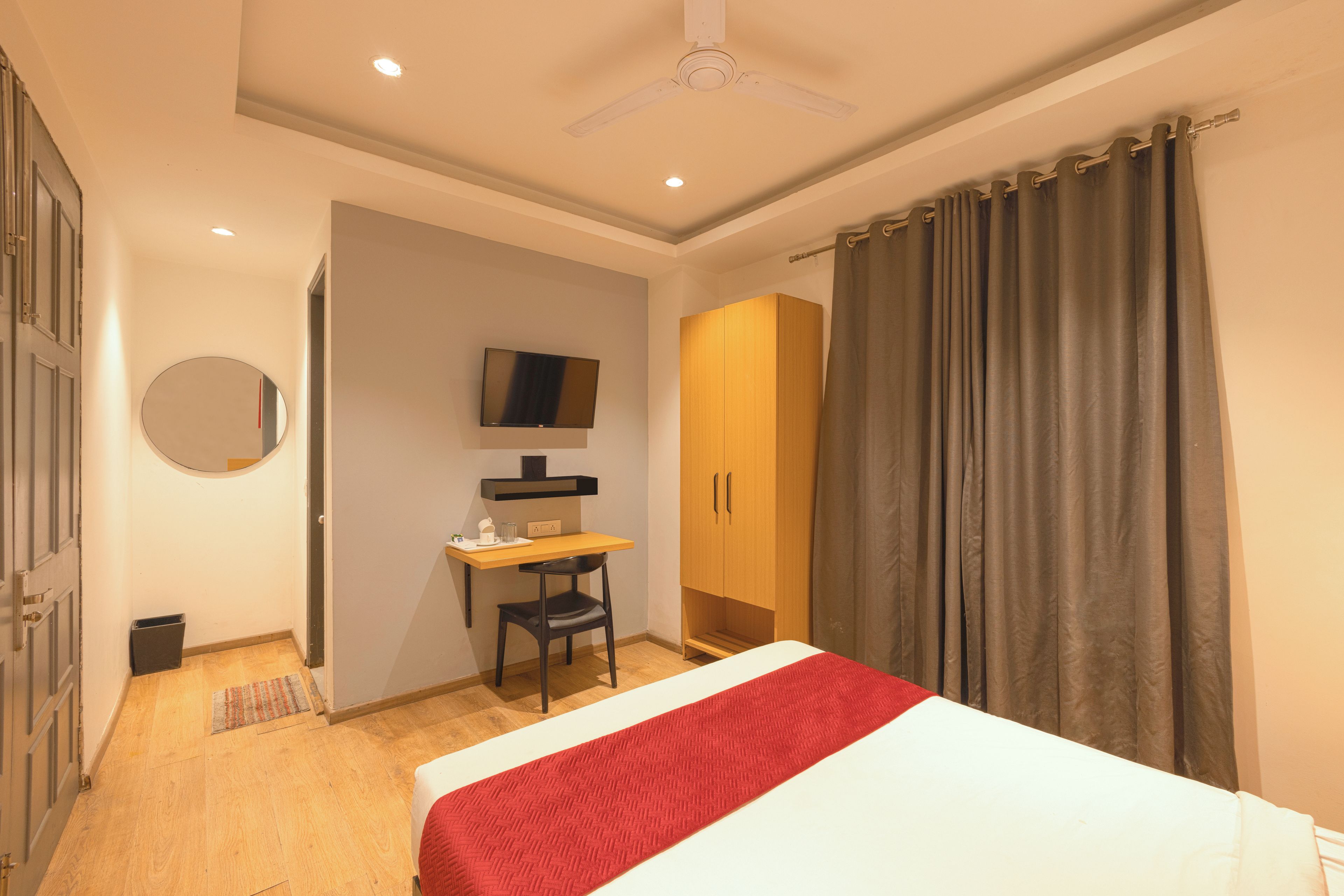 Une chambre à coucher comprenant un lit, un bureau, une chaise, une armoire, un téléviseur et un ventilateur de plafond.
