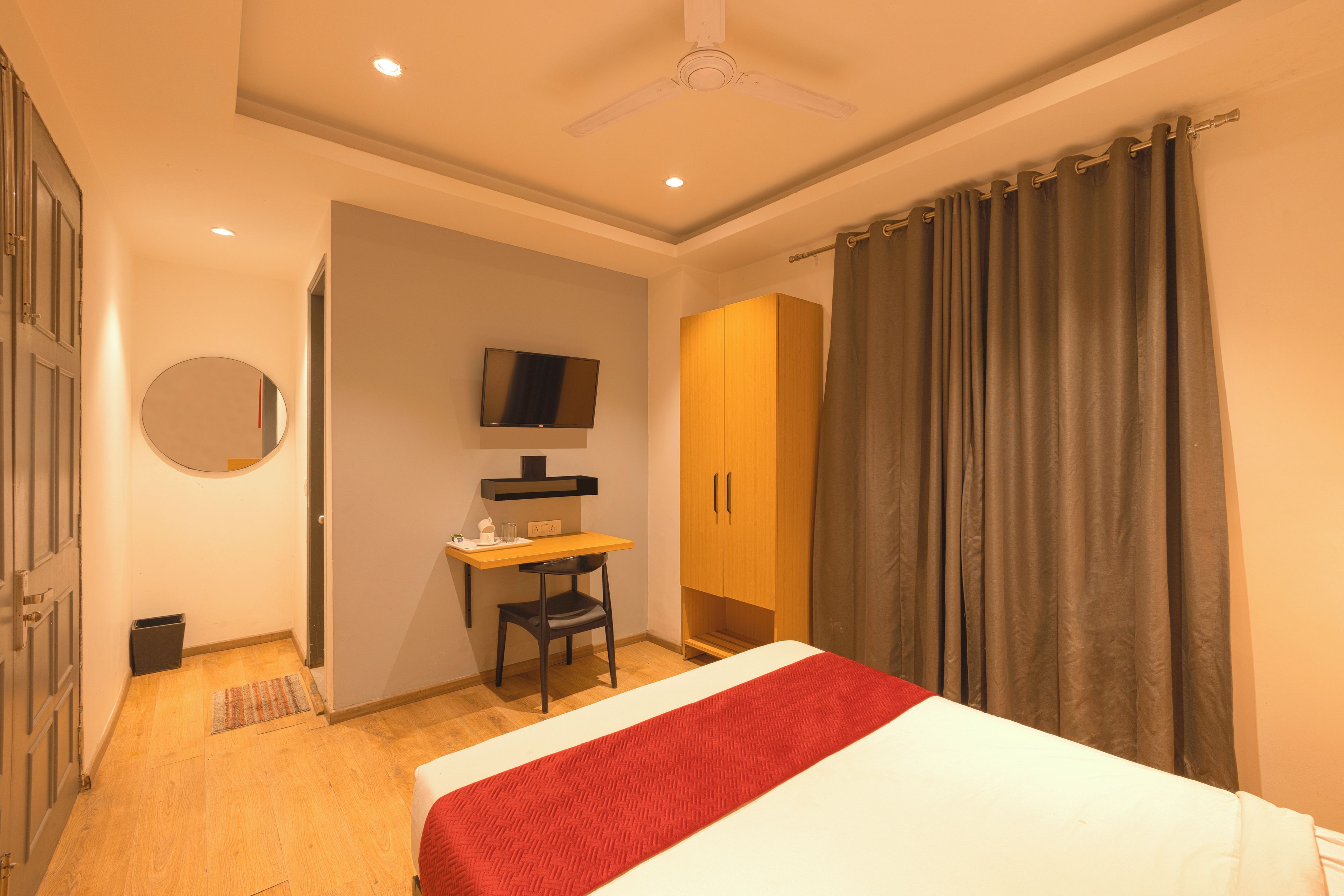 Une chambre d’hôtel équipée d’un lit, d’un bureau, d’une chaise, d’une armoire, d’une télévision et d’un ventilateur de plafond.