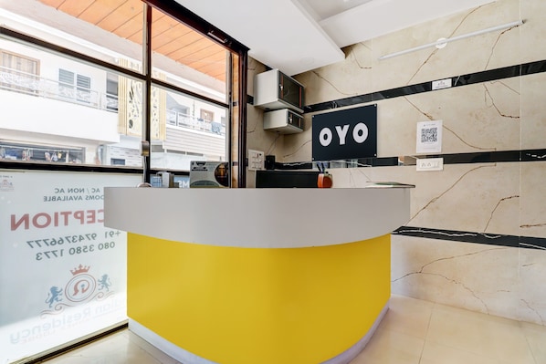 Bancada de recepção com uma placa indicando 'OYO' e um código QR na parede.