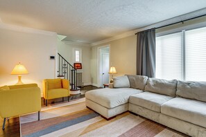 A living room with a sofa, armchair, and lamps. There is a staircase leading to another room. - Historic Detroit Charm Near Area Hospitals (Detroit)