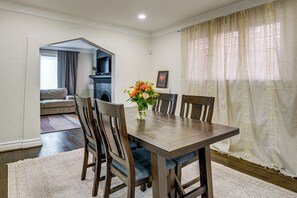 A dining area with a wooden table, chairs, and a vase of flowers. - Historic Detroit Charm Near Area Hospitals (Detroit)