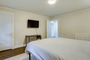 A bedroom with a bed, a television mounted on the wall, and a door leading to another room. - Historic Detroit Charm Near Area Hospitals (Detroit)
