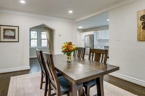 A dining area with a wooden table, chairs, and a vase of flowers. - Historic Detroit Charm Near Area Hospitals (Detroit)
