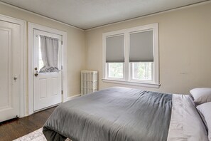 A bedroom with a bed, a radiator, and a window with blinds. - Historic Detroit Charm Near Area Hospitals (Detroit)