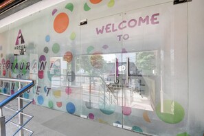 Un muro de vidrio con patrones circulares de colores y el texto 'WELCOME TO' sobre una puerta.
