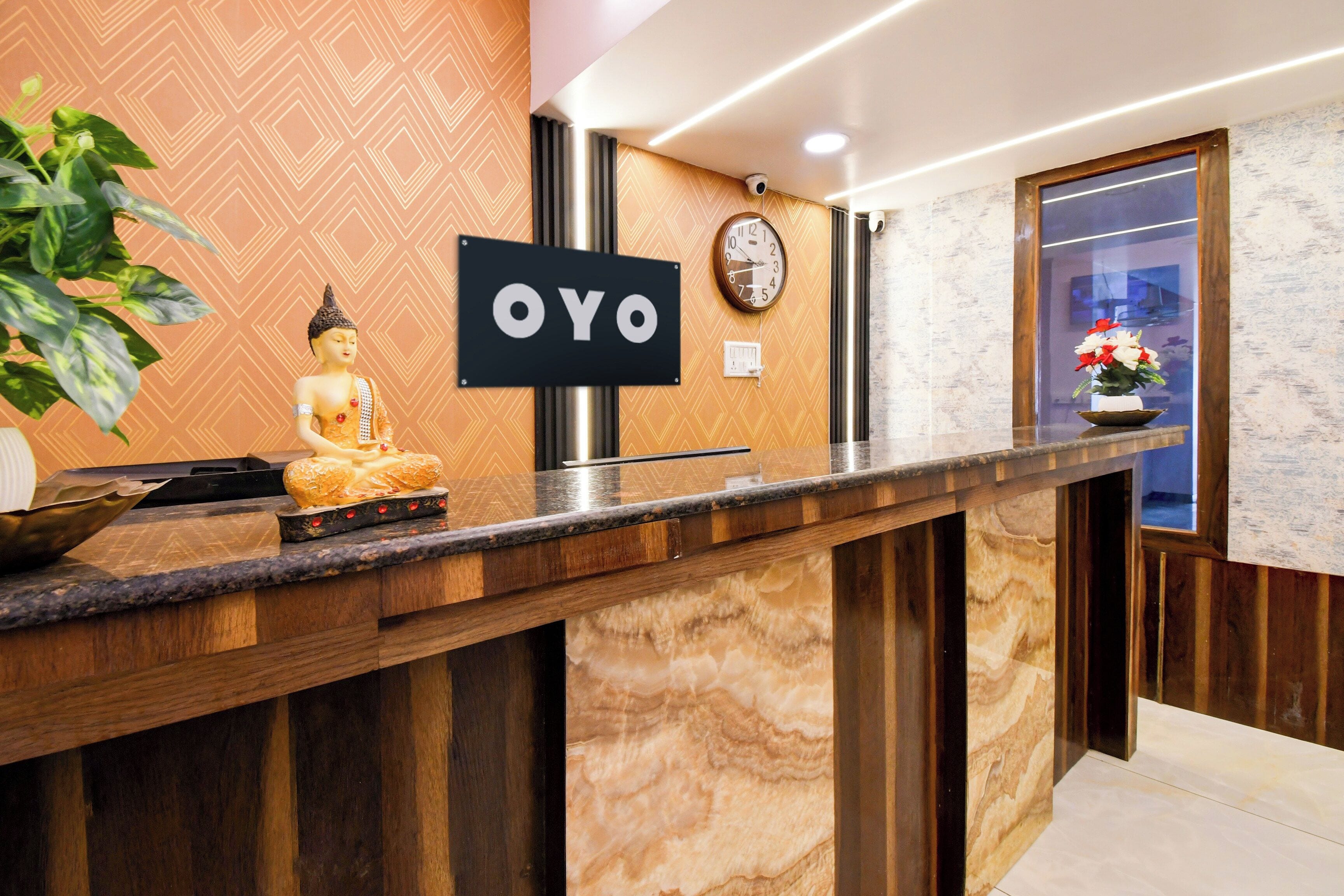 A reception desk with a Buddha statue, a clock, and a sign that reads 'OYO'.