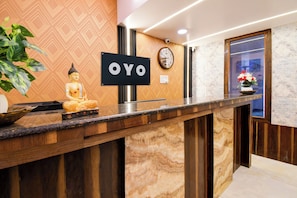 Una recepción con una estatua de Buda, un reloj y un cartel que dice 'OYO'.