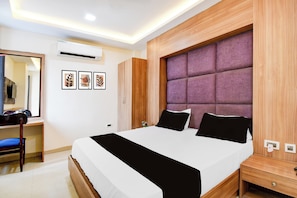 A modern bedroom with a large bed, a wooden wardrobe, a desk, and a mirror. - OYO 835663 Hotel Drishti Grand (Lucknow)