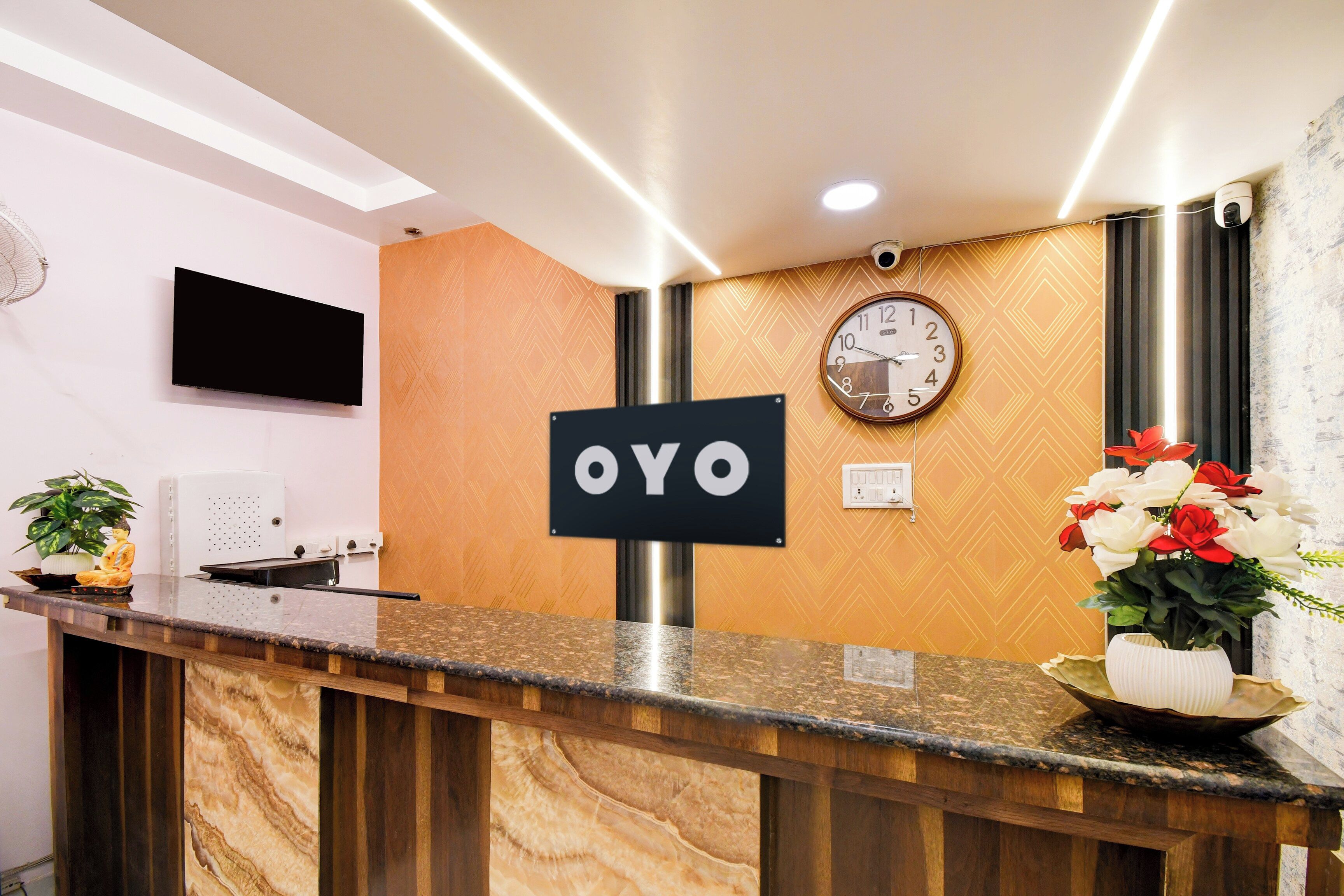 Een receptiebalie met een 'OYO' bord, een klok en een potplant.