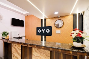 A reception desk with a 'OYO' sign, a clock, and a potted plant. - OYO 835663 Hotel Drishti Grand (Lucknow)