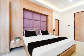 Un dormitorio moderno con una cama grande, cabecera de madera y una mesita de noche con un florero.