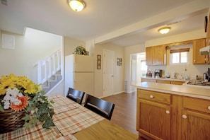 A kitchen with wooden cabinets, a dining area with a table set for two, and a staircase leading to another level. - 'The Little House on The Prairie' Mtn View! (Peyton)