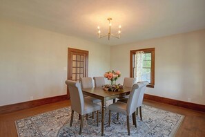 A dining room with a wooden table, six chairs, a chandelier, and two windows with curtains. - 1 Mi to Culver-Stockton College: Home w/ Yard (Canton)