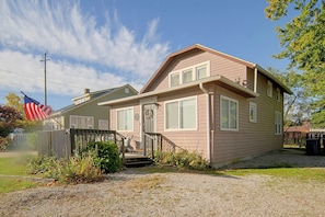 A two-story house with a front porch, a flag, and a small garden area. - Lake Erie Days, Fireside Nights! Geneva Getaway (Geneva)