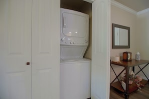 A laundry room with stacked appliances, a wooden table with a mirror, and a vase. - Eucha Home: Grand Lake Views, Boat Ramp Access (Eucha)
