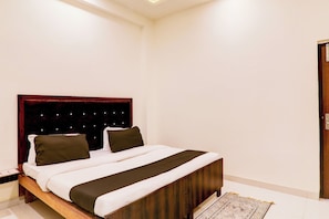 A bedroom with a bed, wooden headboard, and a patterned rug. - Hotel O KAILASHA INN (Lucknow)