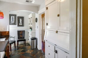 A kitchen with a refrigerator, a chair, a trash bin, and a wall-mounted clock. - Walk to Pickleball, Parks, Pubs! Cozy Dtwn Apt (Bakersfield)