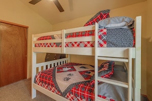 A bunk bed with a red and black patterned bedspread and a gray pillow. - Walk to Midtown! Family Getaway w/ Wraparound Deck (Ruidoso)