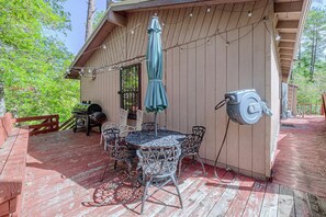 Eine Terrasse mit einem runden Tisch und Stühlen, einem Grill und einer Lichterkette.
