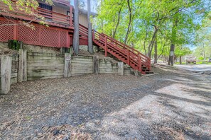 A wooden staircase with a red handrail leading up to a building with a lattice facade. - Walk to Midtown! Family Getaway w/ Wraparound Deck (Ruidoso)