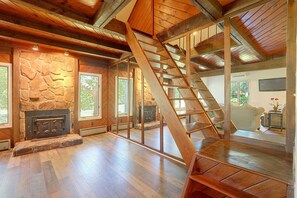 A spacious interior with a wooden staircase, stone fireplace, and large windows. - Lake Hartwell Home w/ Quiet Patio & Lake Access (Townville)