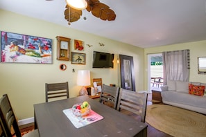 A dining area with a table set for two, a sofa, and a television mounted on the wall. - Pet-Friendly Central Home w/ Fenced Yard! (San Diego)