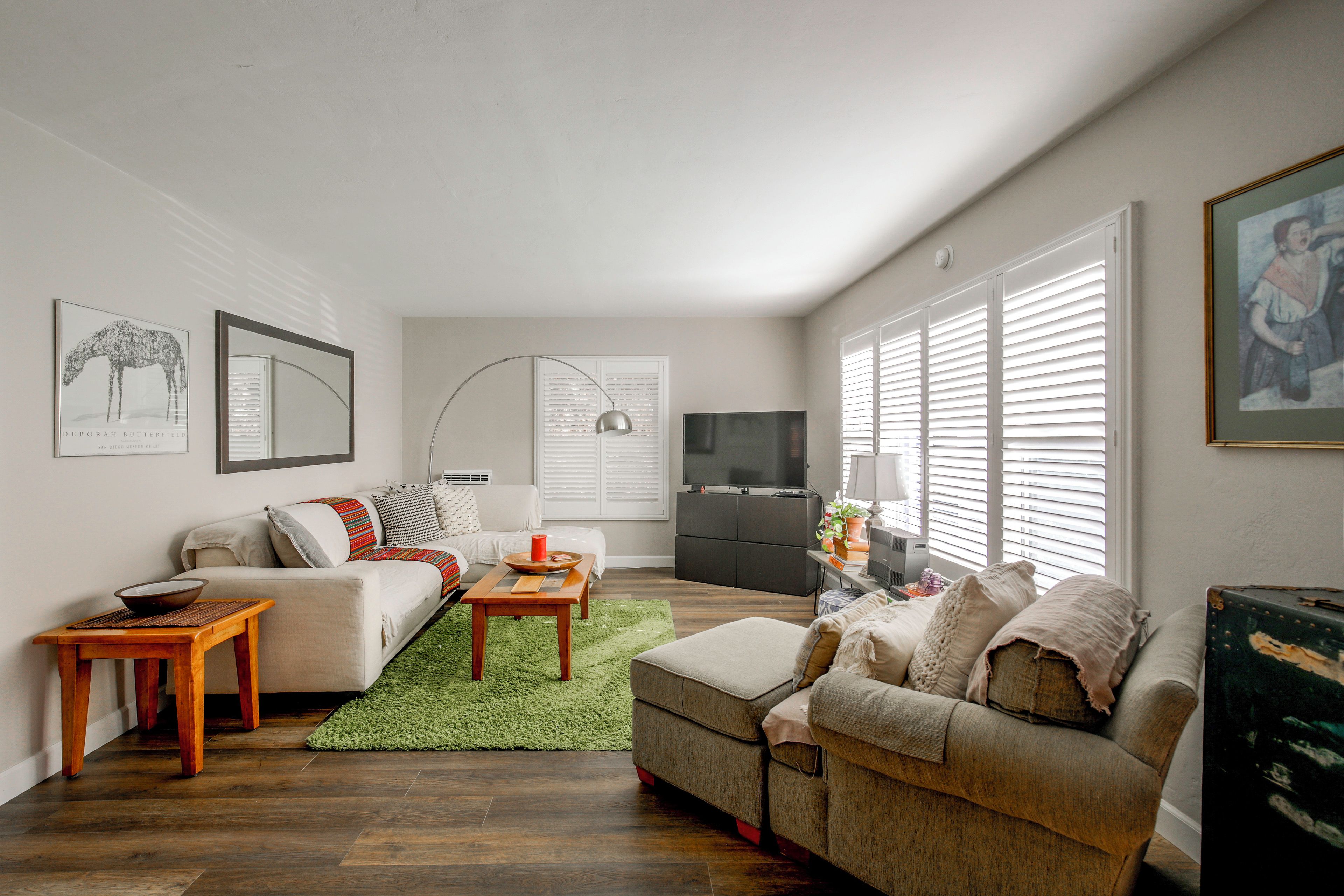 A living room with a sofa, a coffee table, a TV, and artwork on the walls.