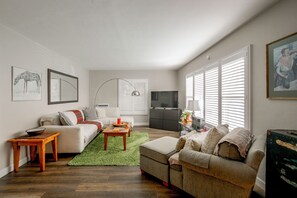 A living room with a sofa, a coffee table, a TV, and artwork on the walls. - Pet-Friendly Central Home w/ Fenced Yard! (San Diego)