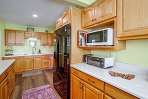 A kitchen with wooden cabinets, a refrigerator, a microwave, and a toaster. - Pet-Friendly Central Home w/ Fenced Yard! (San Diego)