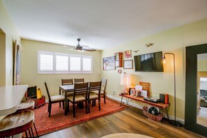 Uma sala de jantar com mesa, cadeiras e ventilador de teto.
