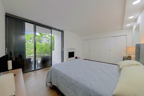A modern bedroom with a large bed, a sliding glass door leading to a balcony, and a white wardrobe. - Relax Poolside, Walk to Ocean! Hillsboro Beach Gem (Hillsboro Beach)