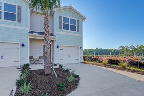 A two-story house with a garage, a small patio with chairs, and a palm tree. - 2 Mi to Panama City Beach: Modern Townhome (Panama City Beach)
