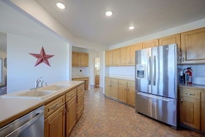 A kitchen with wooden cabinets, stainless steel appliances, and a tiled floor. - Helena Valley Home w/ Mtn Views & Acre (Clancy)