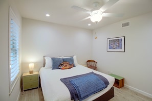 A bedroom with a bed, a nightstand, a chair, a ceiling fan, and a framed picture on the wall. - Aransas Bayfront,  Fishing Pier and Boat Ramp (Rockport)