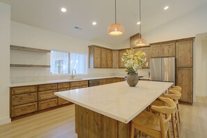 A modern kitchen with wooden cabinets, a large island, stainless steel appliances, and pendant lighting. - Bring Your Boat! Home w/ Patio Near Lake Almanor (Chester)