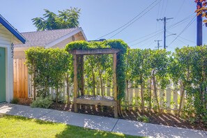 A wooden pergola with climbing plants, a wooden fence, and a house with a green door. - North Hollywood Home, Extended Stay (Los Angeles)
