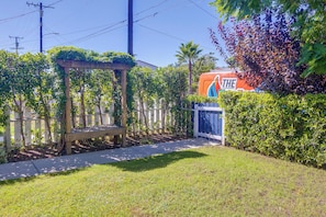 A garden with a wooden pergola, a bench, and a pathway leading to a building with a colorful sign. - North Hollywood Home, Extended Stay (Los Angeles)