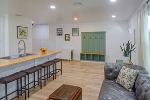 A modern kitchen with a bar area, wooden flooring, and a green door. - North Hollywood Home, Extended Stay (Los Angeles)
