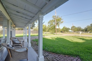 A covered patio area with wicker furniture and a view of a grassy park. - Steps to Cove Park Boat Ramp! Kemah Home w/ Yard (Kemah)