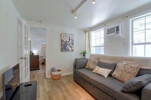 A living room with a sofa, a television, and a door leading to another room. - Steps to Cove Park Boat Ramp! Kemah Home w/ Yard (Kemah)