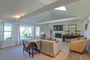 A spacious living room with a large window, a sofa, a coffee table, and a fireplace. - Steps to Cove Park Boat Ramp! Kemah Home w/ Yard (Kemah)
