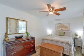 A bedroom with a bed, dresser, mirror, ceiling fan, and a wall-mounted air conditioner. - Steps to Cove Park Boat Ramp! Kemah Home w/ Yard (Kemah)