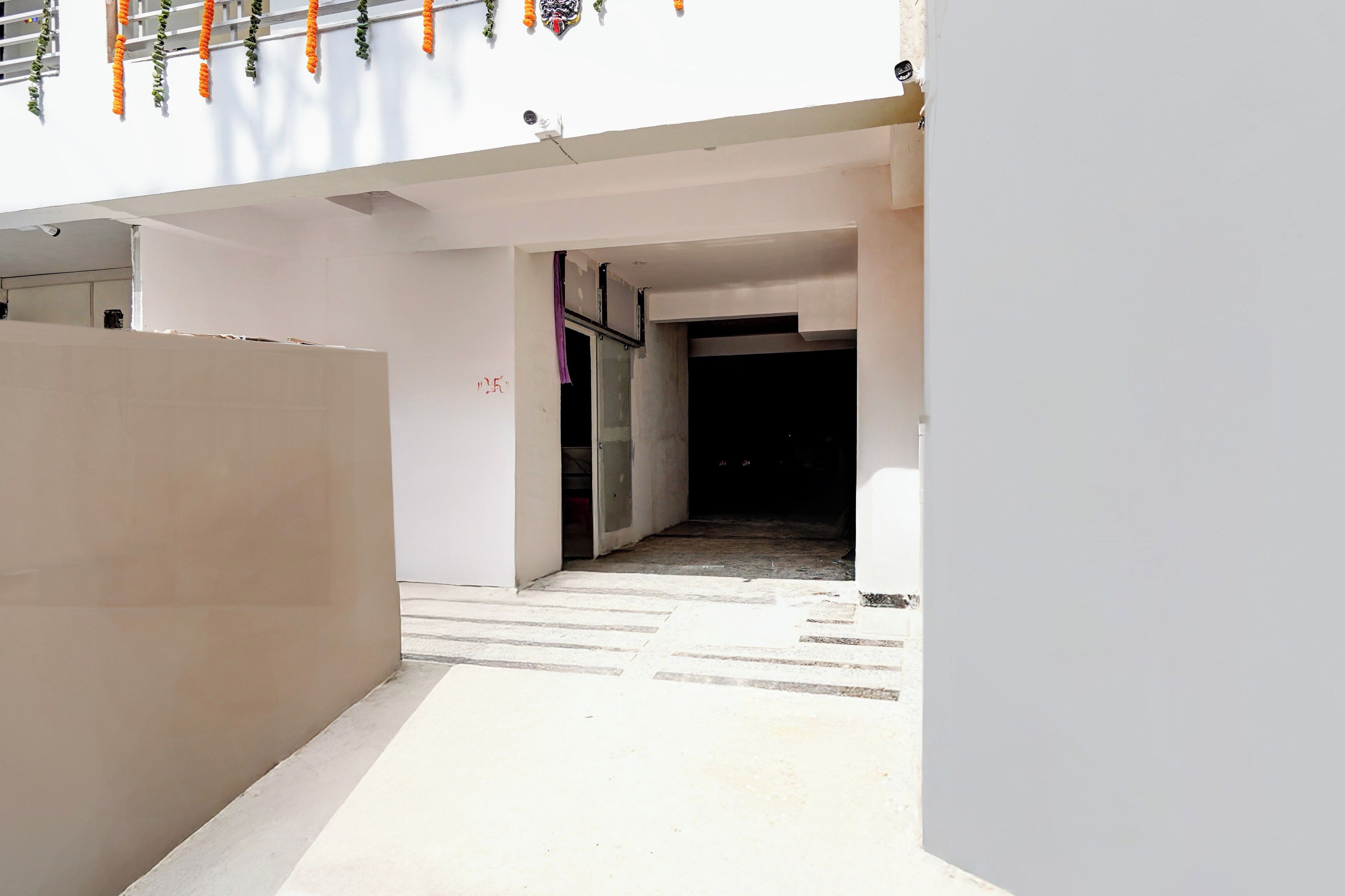 A corridor with a white wall, a door, and a window with a view of the sky.
