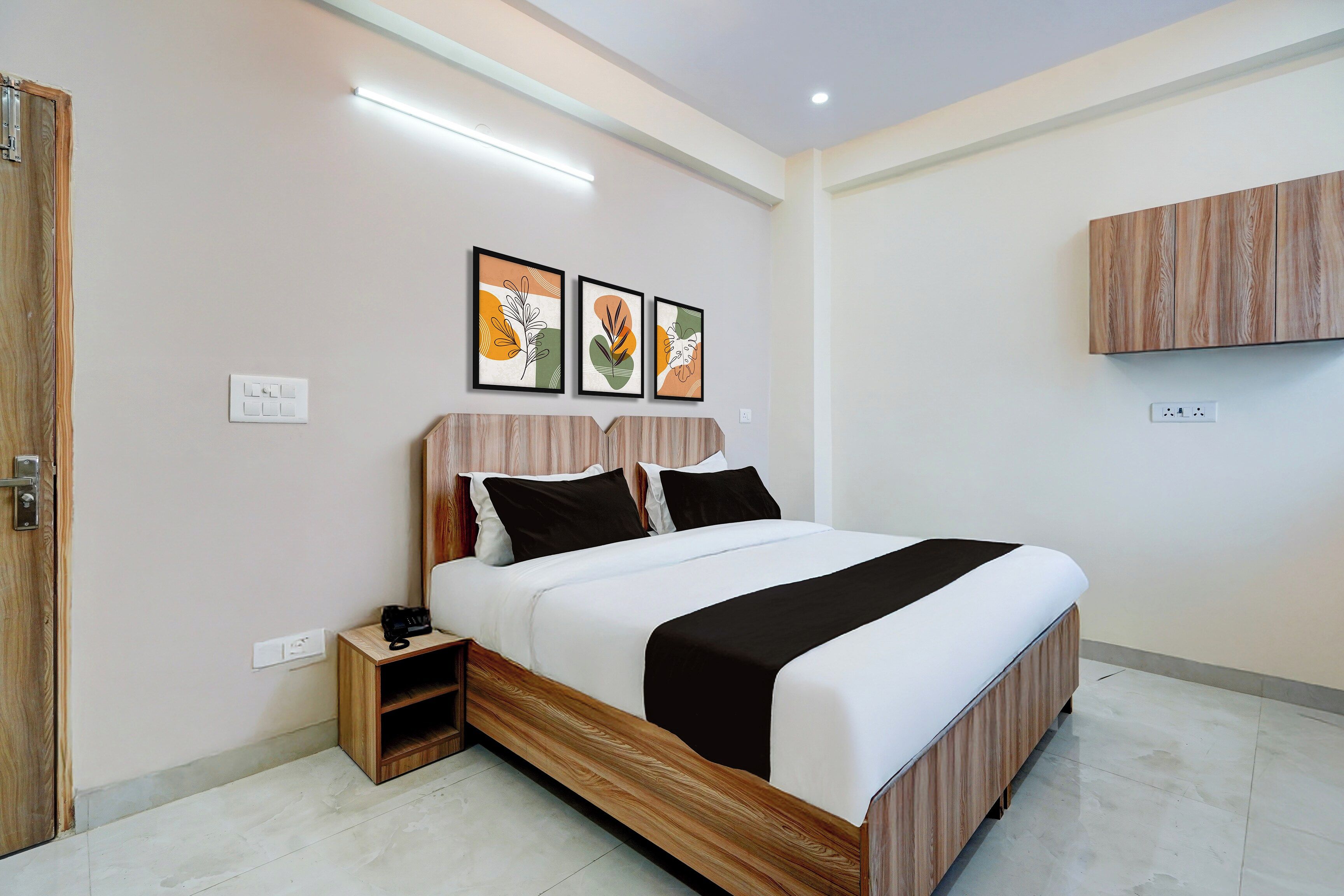 A modern bedroom with a bed, bedside tables, a wardrobe, and artwork on the wall.