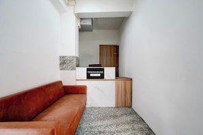 Un área de recepción con mostrador de mármol, un mueble de madera y un sofá de cuero rojo.
