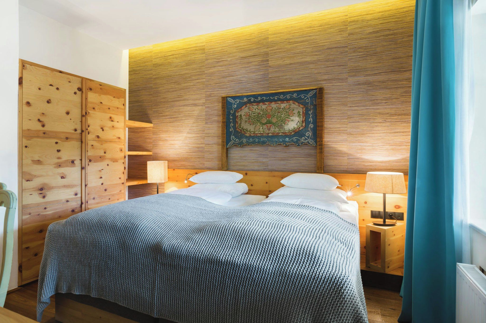 Une chambre d’hôtel avec une tête de lit en bois, un lit avec des oreillers blancs, une table de chevet avec une lampe et une décoration murale.