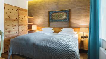 Une chambre d’hôtel avec une tête de lit en bois, un lit avec des oreillers blancs, une table de chevet avec une lampe et une décoration murale.